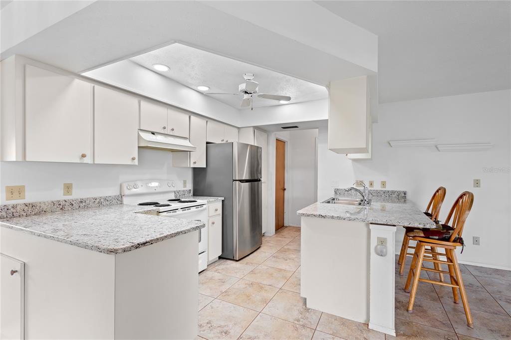A kitchen features white cabinets, granite countertops, stainless steel appliances, and a breakfast bar — 420 DUKE ROAD, VENICE, FL