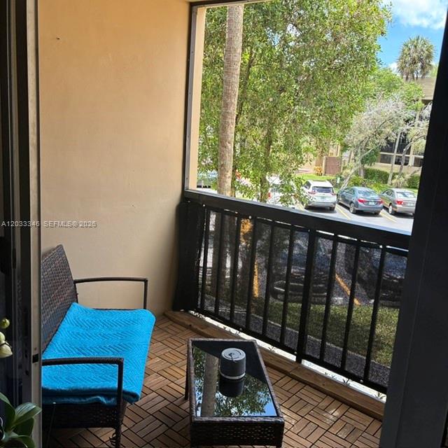 A balcony with wicker furniture, a blue blanket, and a view of a parking lot — 10845 SW 112th Ave, Miami FL 33176, MIAMI, FL