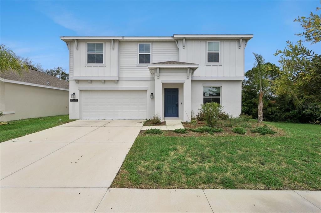 A two-story house with a white exterior, a blue front door, and a two-car garage — 33622 SKY BLOSSOM CIRCLE, LEESBURG, FL