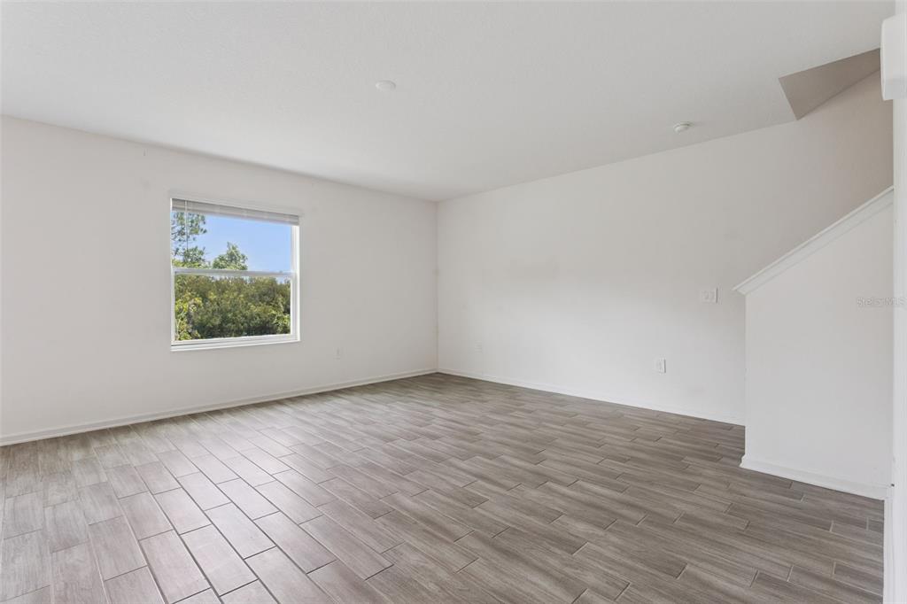 An empty room with light wood-look tile flooring, white walls, and a single window — 33622 SKY BLOSSOM CIRCLE, LEESBURG, FL