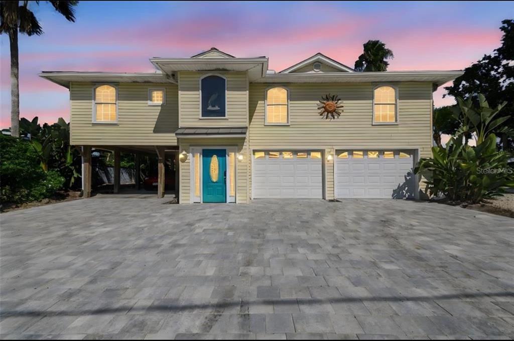 A two-story house with yellow siding, a teal front door, and a paved driveway — 9914 ALAVISTA DRIVE, GIBSONTON, FL