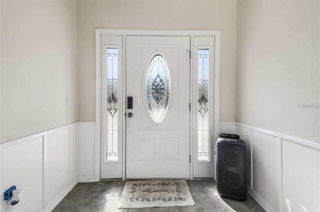 An entryway features a white front door with sidelights, wainscoting, and a dark tiled floor — 9914 ALAVISTA DRIVE, GIBSONTON, FL
