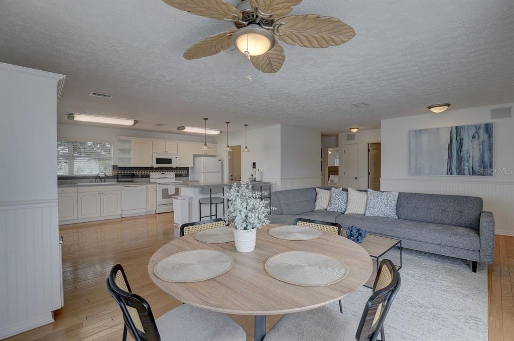 An open-concept living area features a kitchen, dining table, and gray sofa on wood flooring — 9914 ALAVISTA DRIVE, GIBSONTON, FL