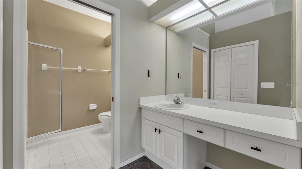 A bathroom features a white vanity with a single sink, a mirror, and a shower — 386 ENCLAVE DRIVE UNIT 386, LAKELAND, FL