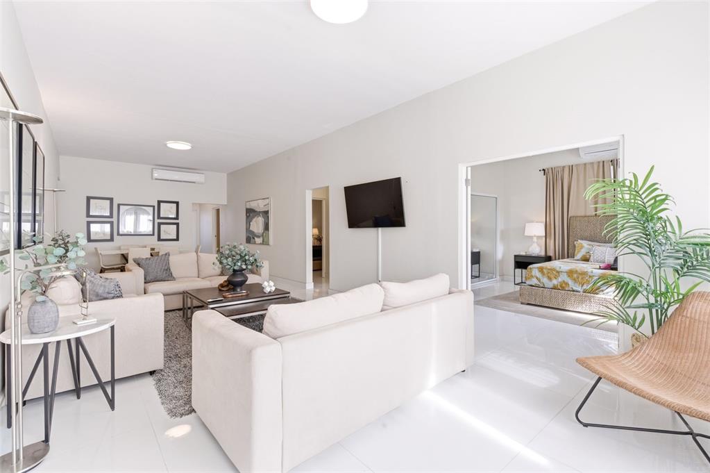 A bright living room with white tile floors opens into a bedroom with a bed — 56 CALLE F KRUG CONDADO UNIT PH-1, SAN JUAN, PR