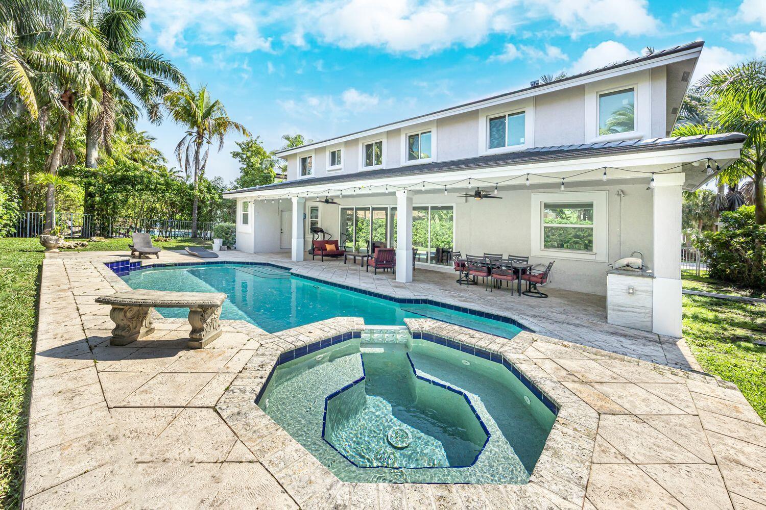 A backyard features a swimming pool, a hot tub, and a covered patio with outdoor furniture — 1879 Hidden Trail Lane, Weston FL 33327, WESTON, FL