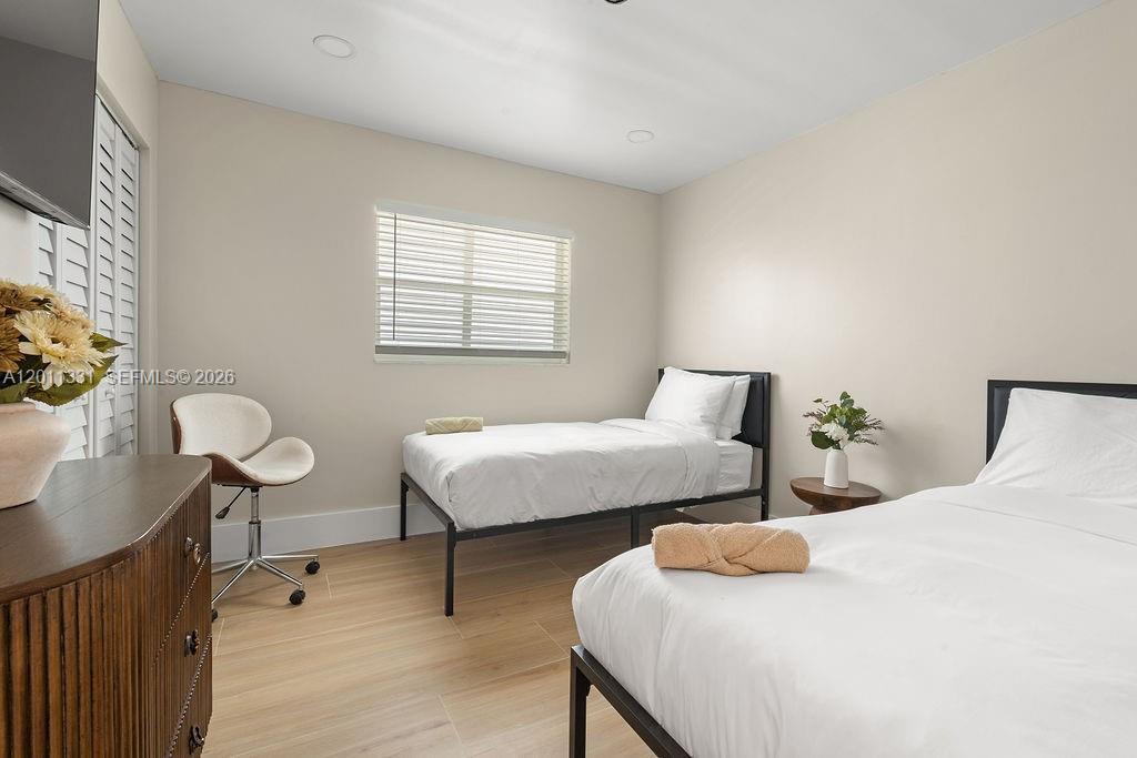 A bedroom features two twin beds, a wooden dresser, a desk chair, and light flooring — 736 Prosperity Farms Rd, North Palm Beach FL 33408, NORTH PALM BEACH, FL