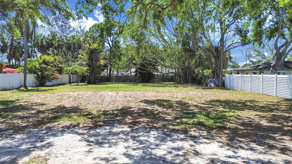 A vacant, sandy residential lot is enclosed by white vinyl fencing and mature trees — 5438 BAYOU GRANDE BOULEVARD NE, ST PETERSBURG, FL