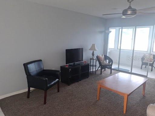 A living room features a black armchair, a television on a stand, and a coffee table — 5245 AMULET DRIVE UNIT 309, NEW PORT RICHEY, FL