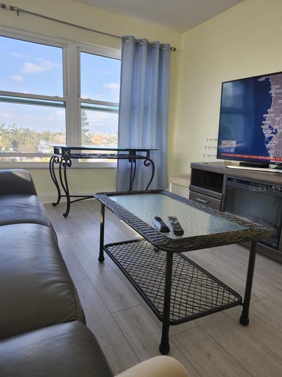 A living room features a wicker coffee table, a glass console table, and a television — 300 64TH AVENUE UNIT 426, ST PETE BEACH, FL