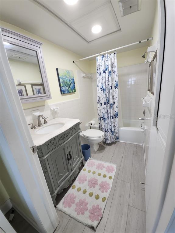 A bathroom features a gray vanity, a floral shower curtain, and a light-colored rug — 300 64TH AVENUE UNIT 426, ST PETE BEACH, FL
