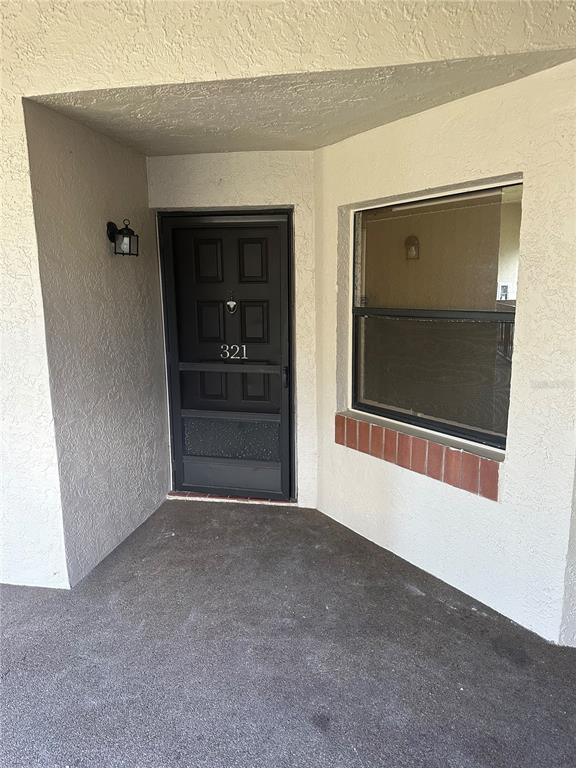 The exterior entrance features a dark door with a screen and a nearby window — 2971 ESTANCIA BOULEVARD UNIT 321, CLEARWATER, FL