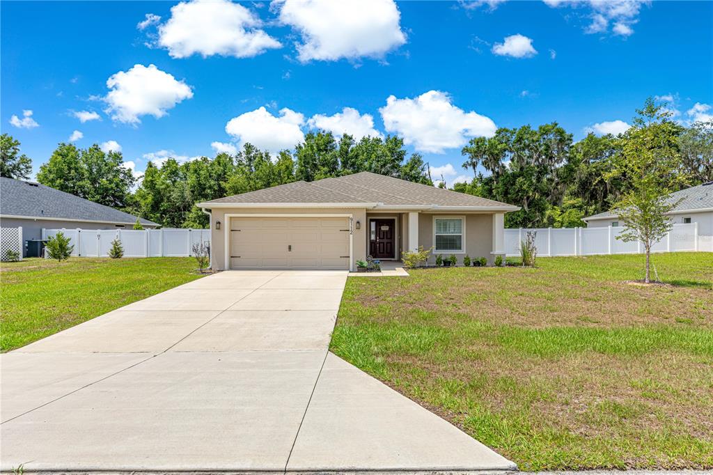 A single-story house with a beige exterior, a two-car garage, and a white vinyl fence — 9112 SE 41ST COURT ROAD, OCALA, FL
