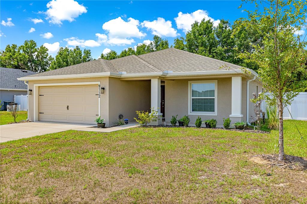 A single-story tan house with a two-car garage and a covered front porch — 9112 SE 41ST COURT ROAD, OCALA, FL