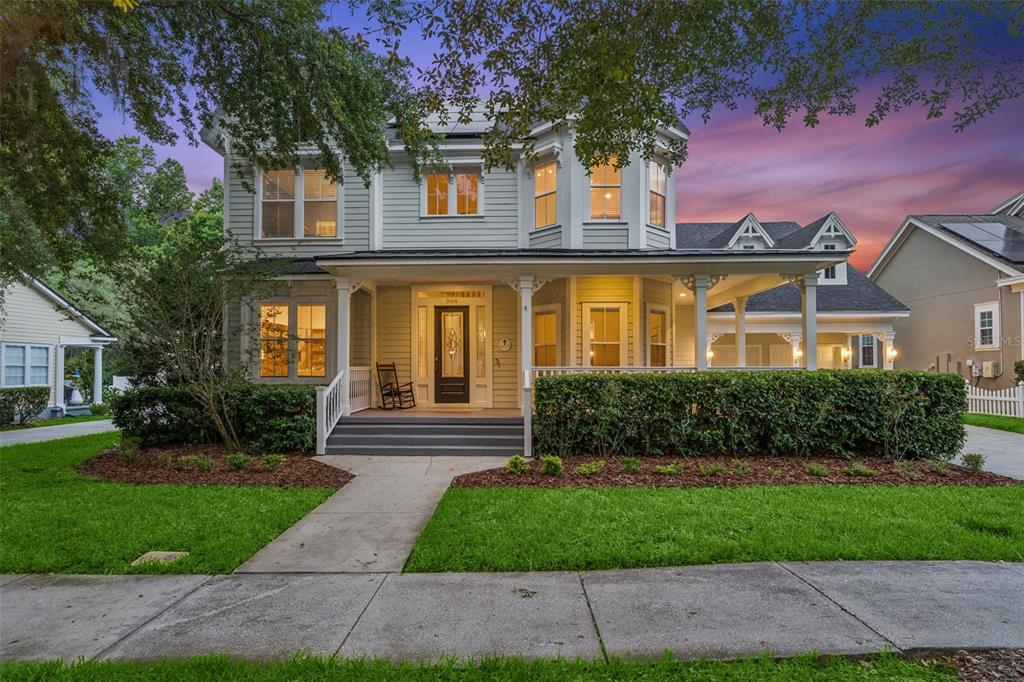 A two-story house with light siding, a wrap-around front porch, and a landscaped front yard — 908 CROTON ROAD, CELEBRATION, FL