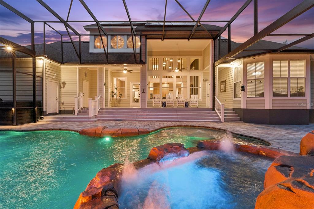 A backyard pool and spa with a screened enclosure and a multi-level house exterior — 908 CROTON ROAD, CELEBRATION, FL