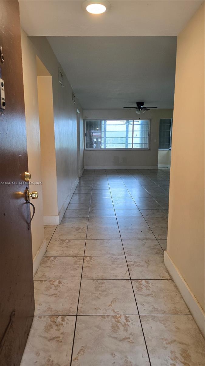 A view from an entryway into a living area with light-colored tile flooring — 1450 NE 191st St # 106, Miami FL 33179, MIAMI, FL