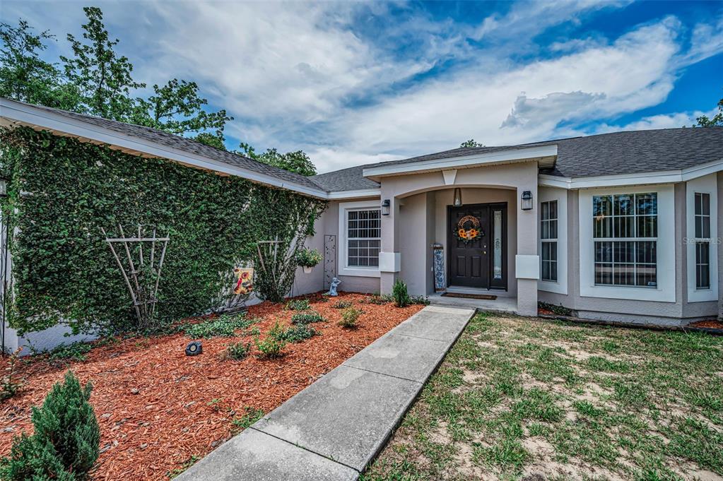 A living room features brown leather sofas, a dark wood entertainment center, and sliding glass doors — 12123 FULMAR ROAD, WEEKI WACHEE, FL