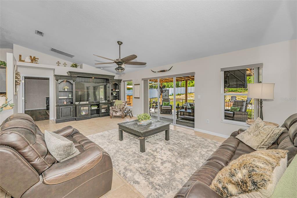 A spacious open-concept living room features tile flooring, a large area rug, and dark furniture — 12123 FULMAR ROAD, WEEKI WACHEE, FL
