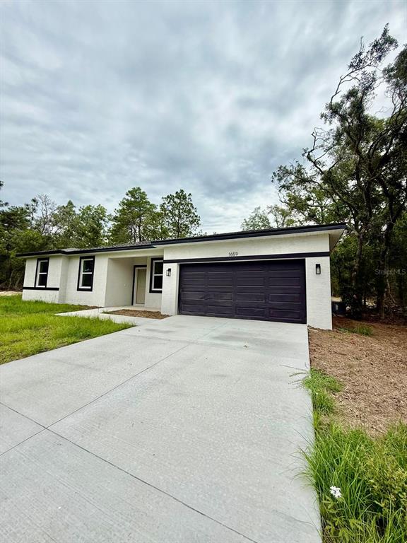 A single-story house with a white exterior, black trim, and a two-car garage — 1659 W BELEN DRIVE, CITRUS SPRINGS, FL