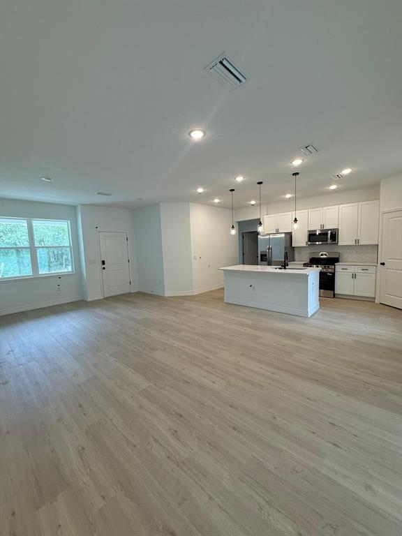 A bright, open-concept kitchen and living area features light wood-look flooring and white cabinetry — 1659 W BELEN DRIVE, CITRUS SPRINGS, FL