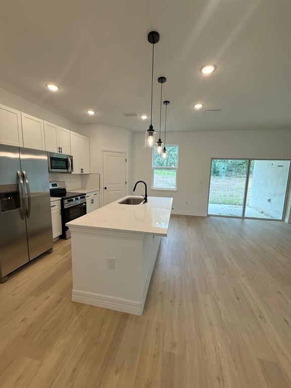 A modern kitchen features white cabinetry, stainless steel appliances, and a central island with seating — 1659 W BELEN DRIVE, CITRUS SPRINGS, FL