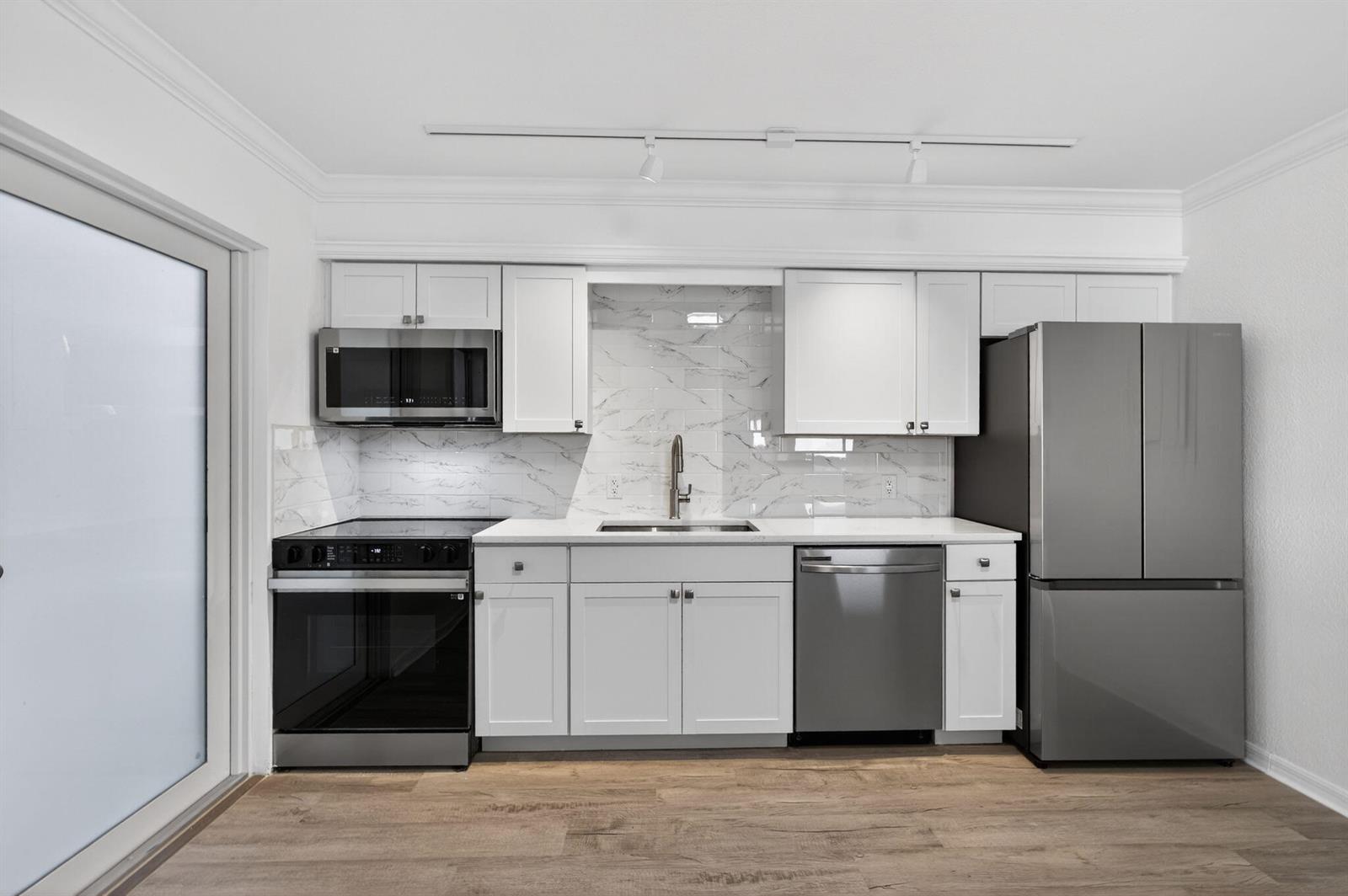 A modern kitchen features white cabinets, stainless steel appliances, and a marble-patterned backsplash — 624 Southwind Circle # 4, North Palm Beach FL 33408, NORTH PALM BEACH, FL