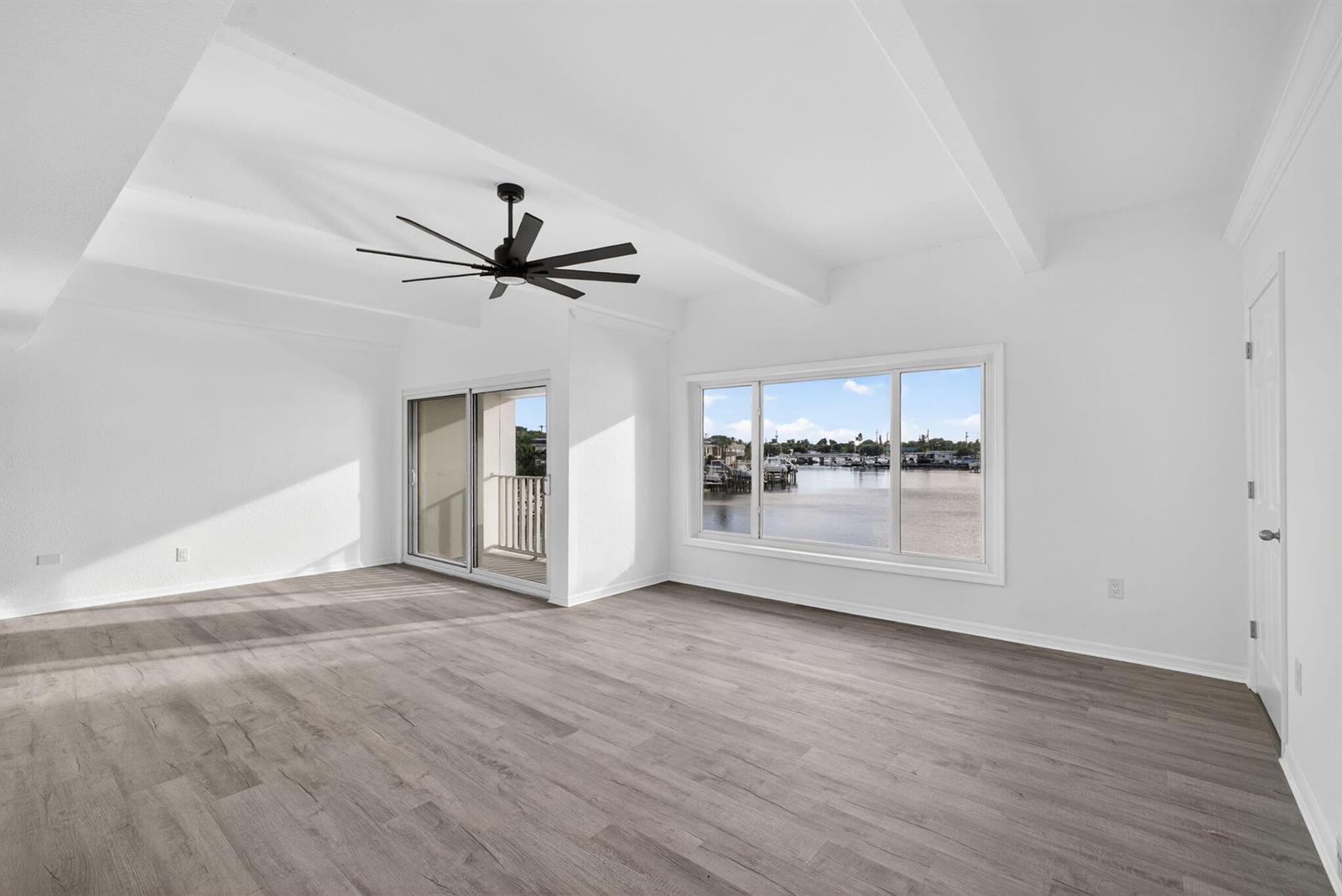 An empty room with white walls, wood-look flooring, a ceiling fan, and waterfront views — 624 Southwind Circle # 4, North Palm Beach FL 33408, NORTH PALM BEACH, FL