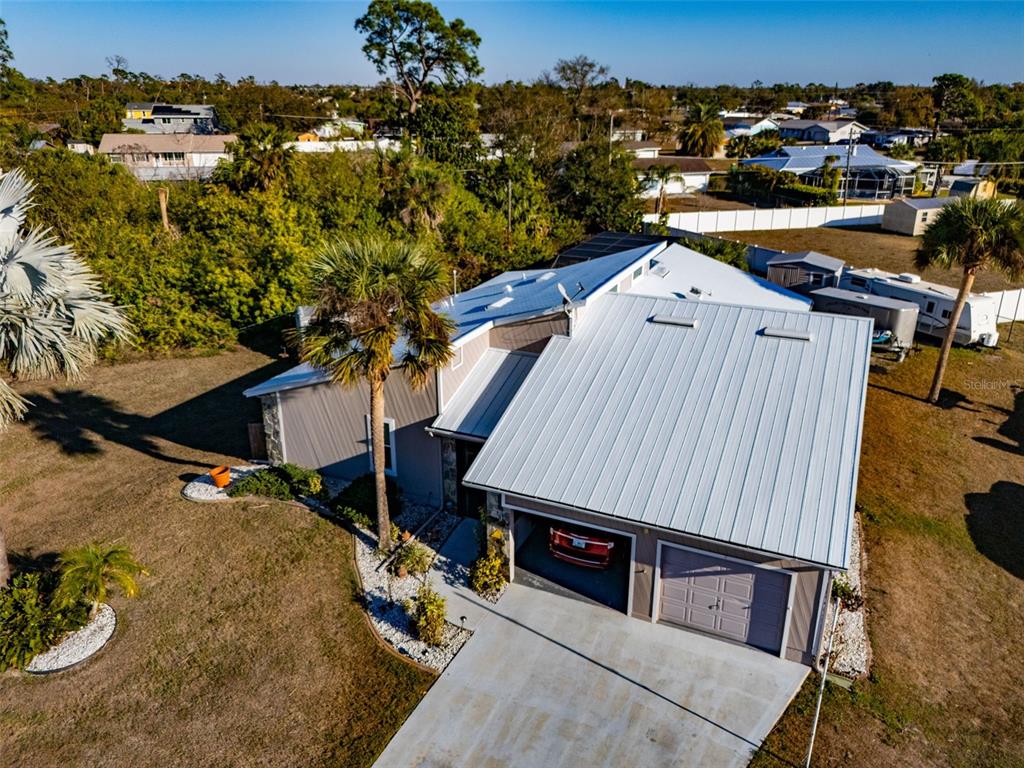 An aerial view shows a house with a metal roof, two-car garage, and palm trees — 643 BLUE LANE NW, PORT CHARLOTTE, FL