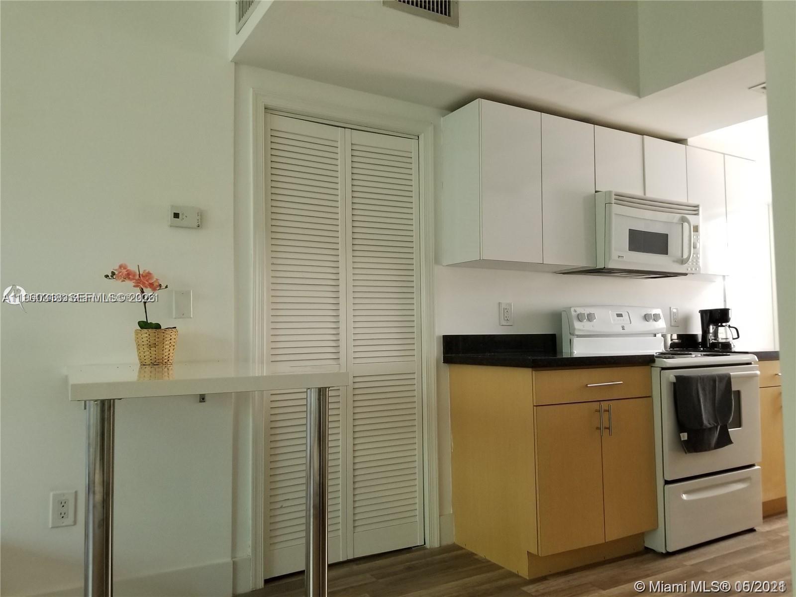 A kitchen features light wood cabinets, white upper cabinets, a microwave, and a small table — 1045 Meridian Ave # 4, Miami Beach FL 33139, MIAMI BEACH, FL