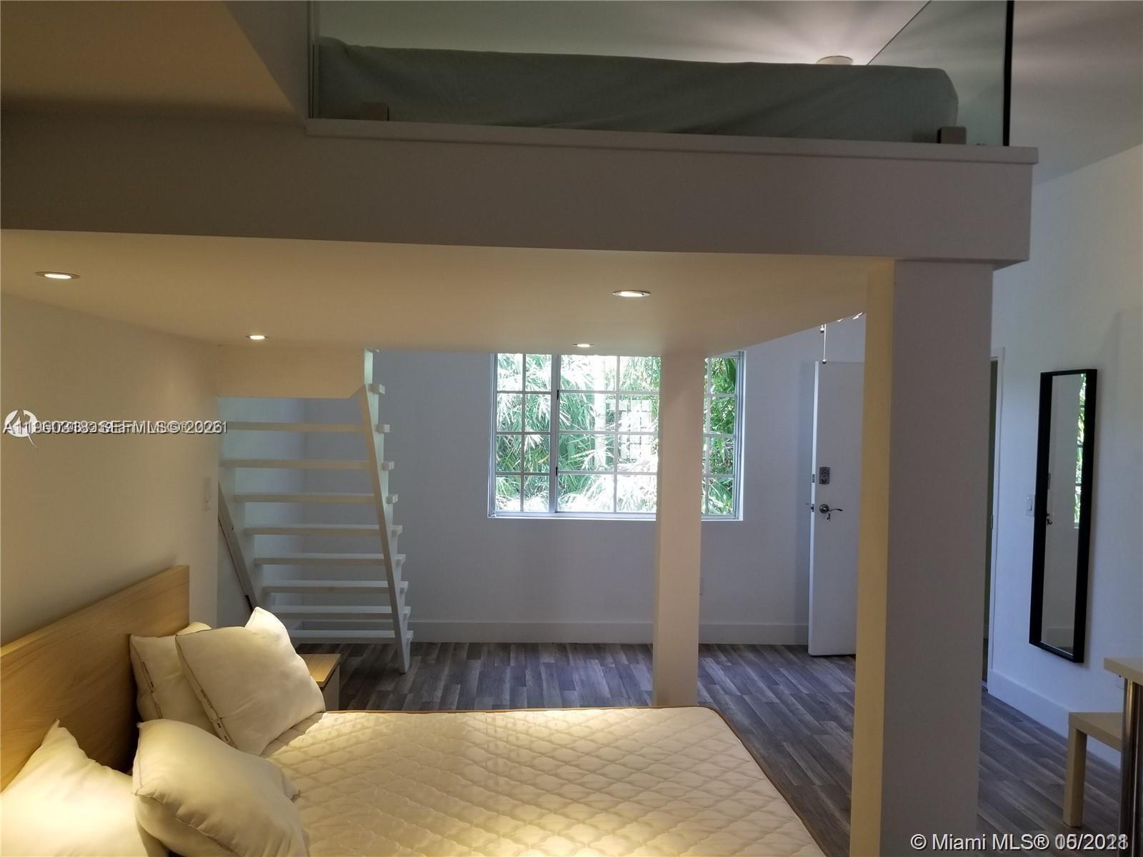 A bedroom features a loft bed area above a main bed with white stairs — 1045 Meridian Ave # 4, Miami Beach FL 33139, MIAMI BEACH, FL