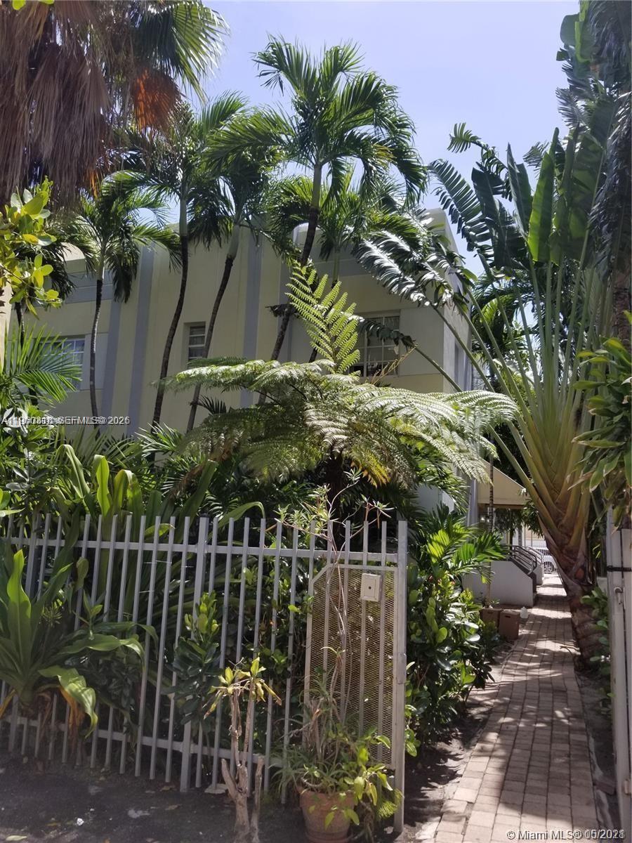 A multi-story building is partially obscured by lush tropical landscaping and a metal fence — 1045 Meridian Ave # 4, Miami Beach FL 33139, MIAMI BEACH, FL