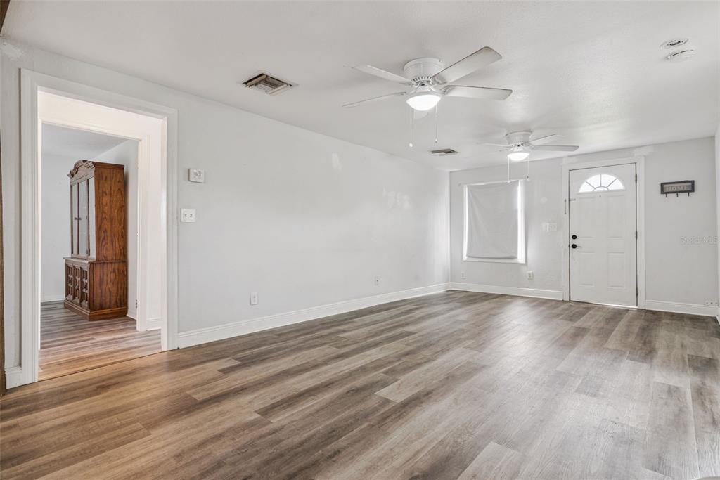 A living room features light gray walls, wood-look flooring, two ceiling fans, and an entryway — 650 S LAKEWOOD AVENUE, OCOEE, FL