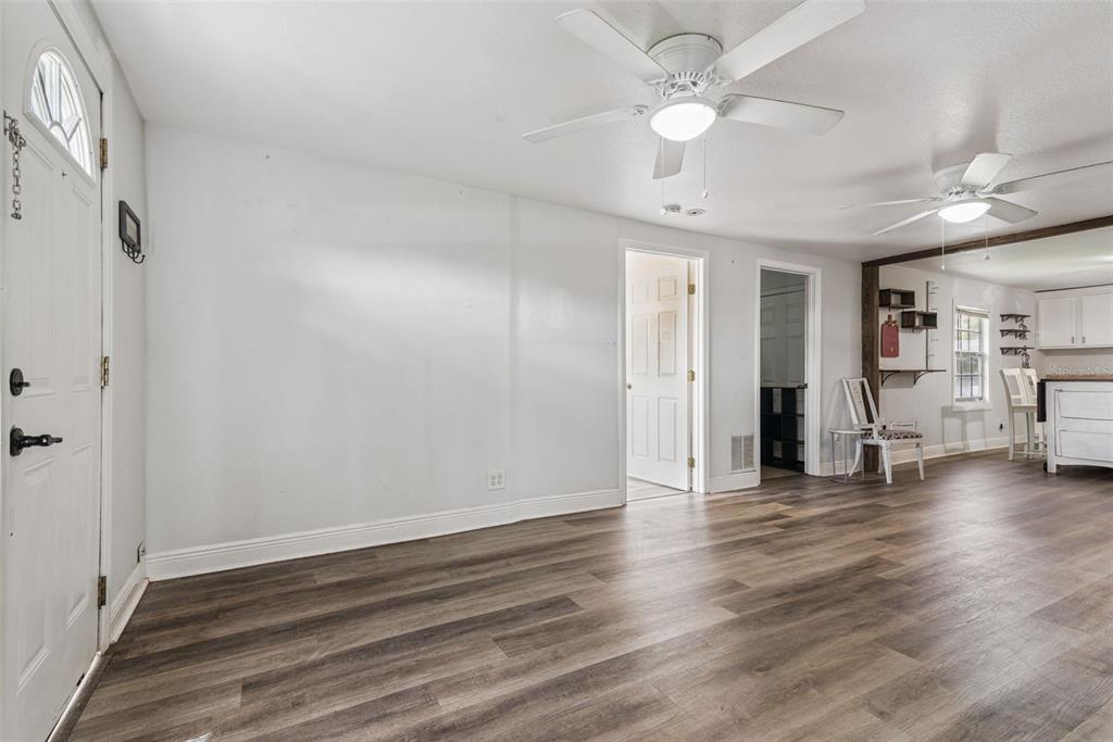 A living room with white walls, wood-look flooring, two ceiling fans, and an adjacent kitchen — 650 S LAKEWOOD AVENUE, OCOEE, FL
