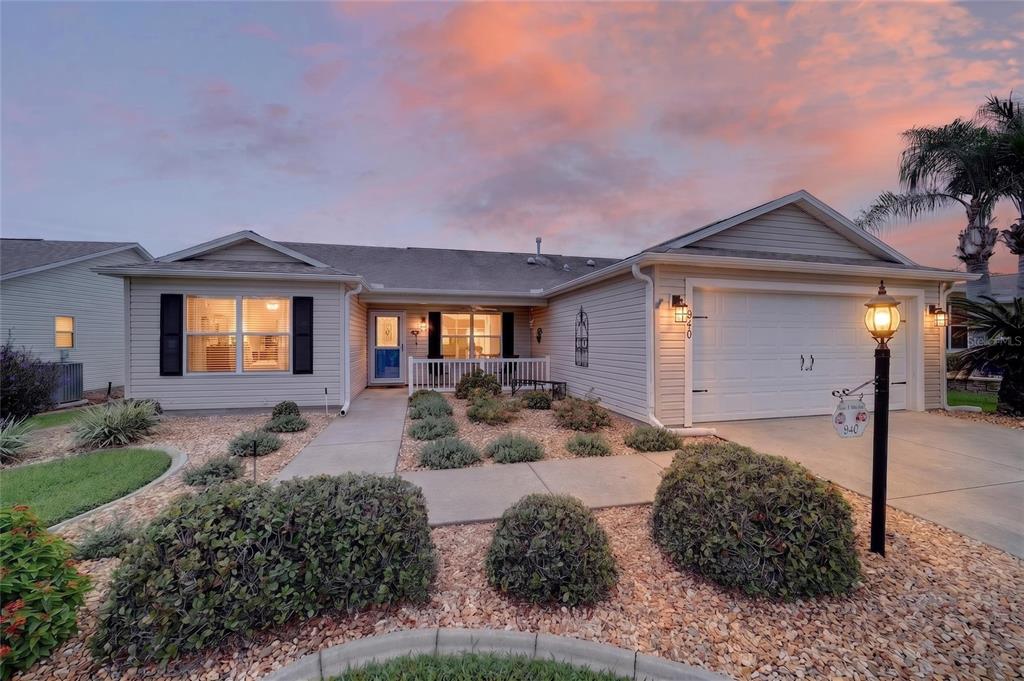 A single-story house with light-colored siding, a two-car garage, and a landscaped front yard — 940 EASTMONT COURT, THE VILLAGES, FL