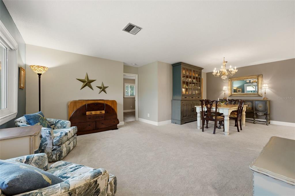A carpeted living and dining area features a hutch, a dining table, and patterned armchairs — 290 CAPRI AVENUE, VENICE, FL