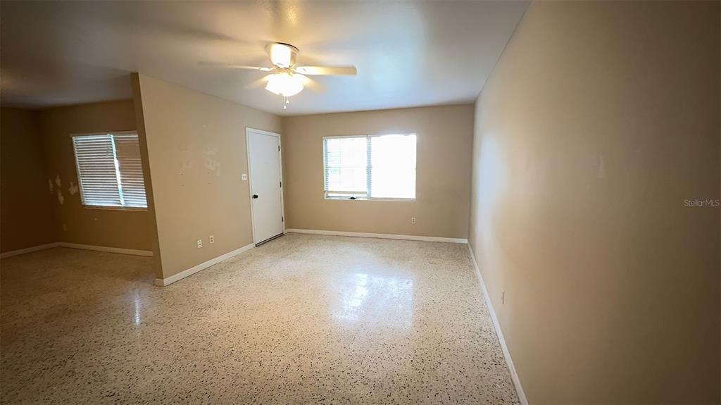 An empty room with beige walls, a ceiling fan, and light-colored speckled flooring — 3330 NW 27TH AVENUE, GAINESVILLE, FL