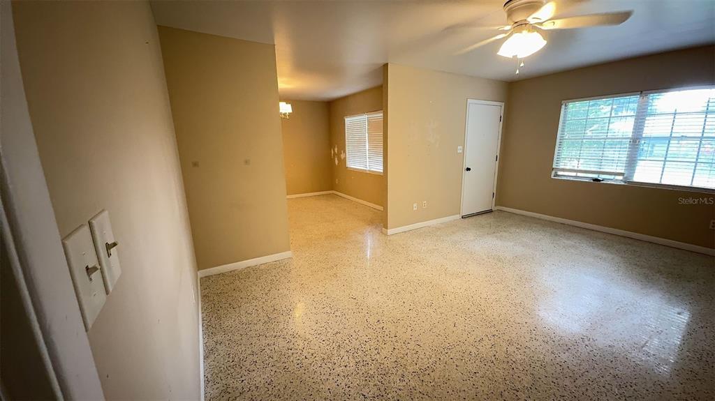 An interior view shows a living room with terrazzo flooring, a ceiling fan, and windows — 3330 NW 27TH AVENUE, GAINESVILLE, FL