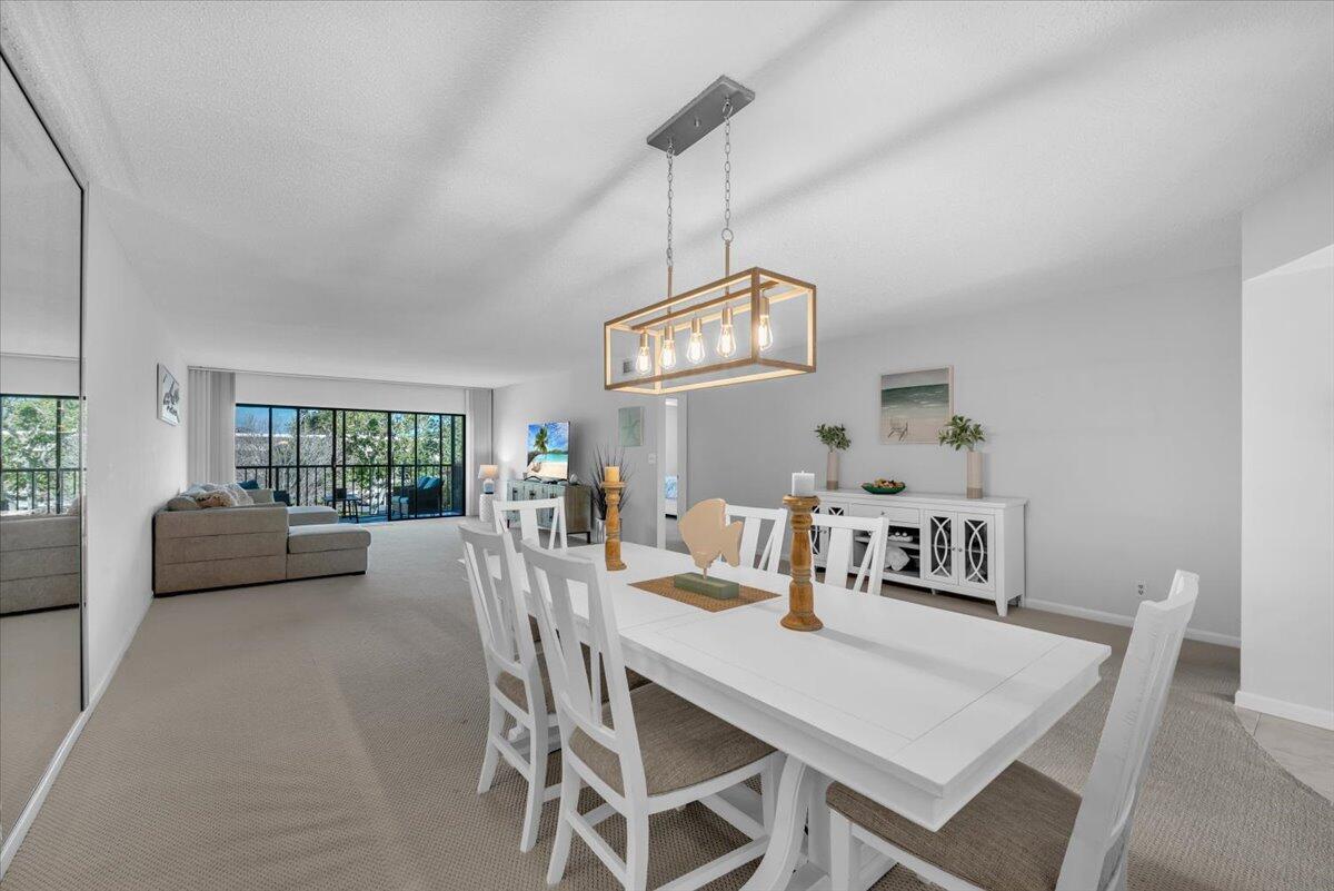 A dining area with a white table and chairs sits beneath a rectangular wooden chandelier — 300 N Highway A1a # 304h, Jupiter FL 33477, JUPITER, FL
