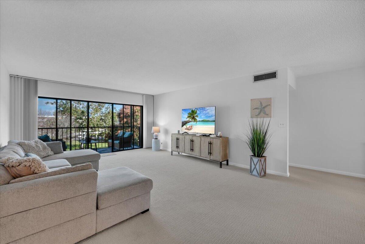 A living room features a sectional sofa, a television on a console, and a balcony — 300 N Highway A1a # 304h, Jupiter FL 33477, JUPITER, FL