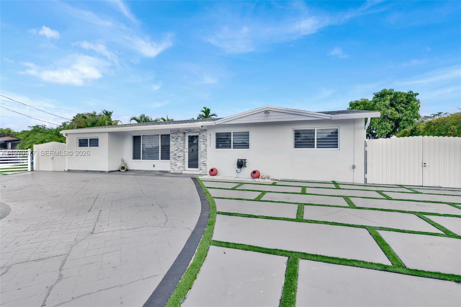 A white single-story house features a paved driveway with grass strips and a stone accent wall — 5521 SW 104th Ave, Miami FL 33165, MIAMI, FL