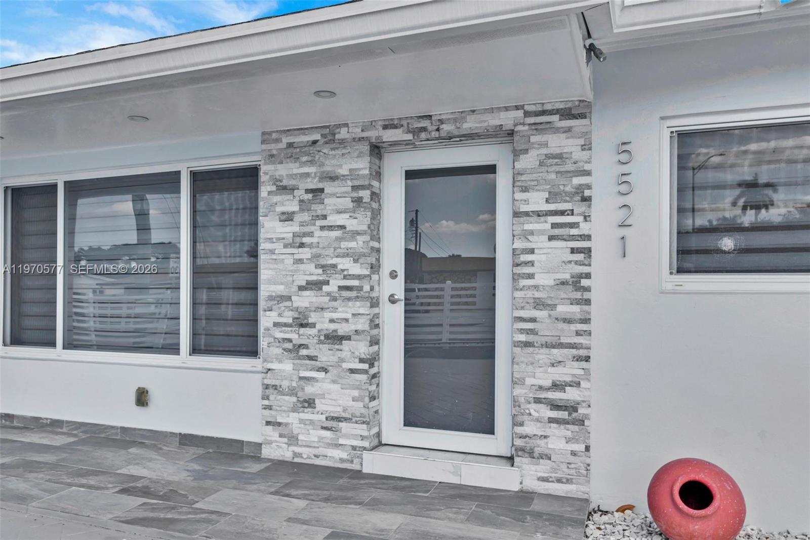 The exterior of a house features a stone-tiled entryway, a glass door, and large windows — 5521 SW 104th Ave, Miami FL 33165, MIAMI, FL