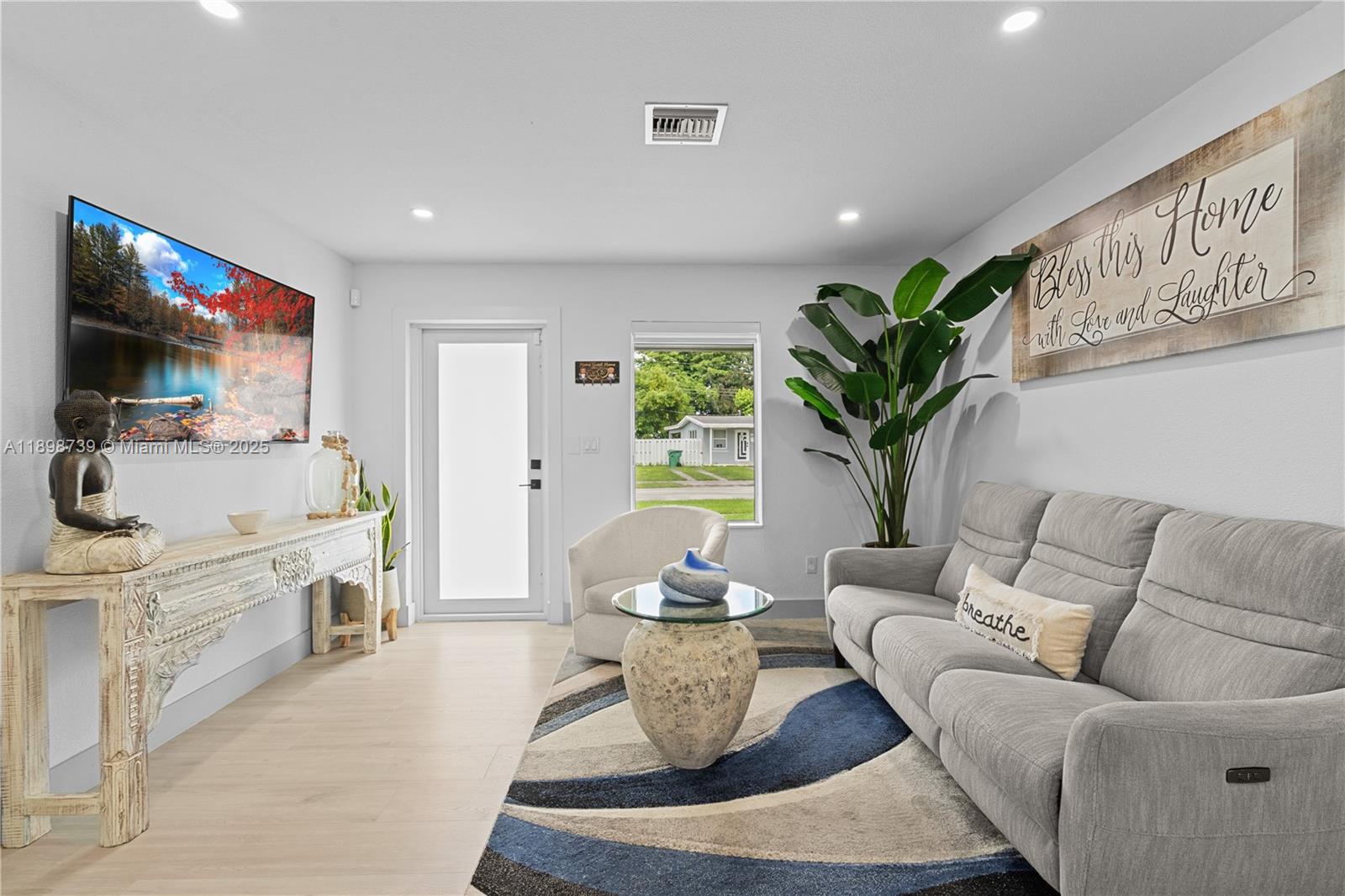 A living room features a gray sofa, a patterned rug, and a wall-mounted television — 11350 SW 57th St, Miami FL 33173, MIAMI, FL