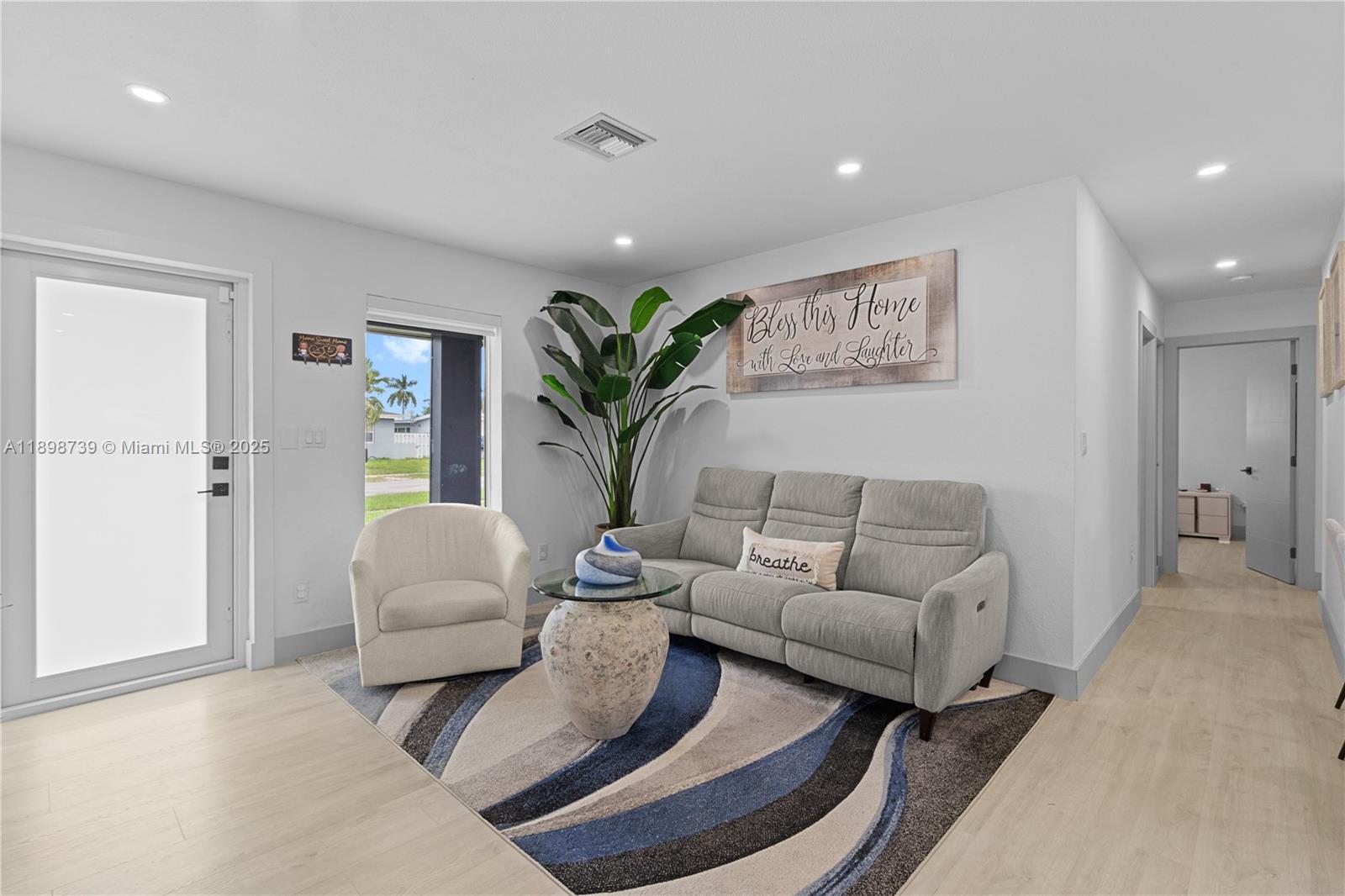 A living room features a gray sofa, a white armchair, and a blue patterned rug — 11350 SW 57th St, Miami FL 33173, MIAMI, FL