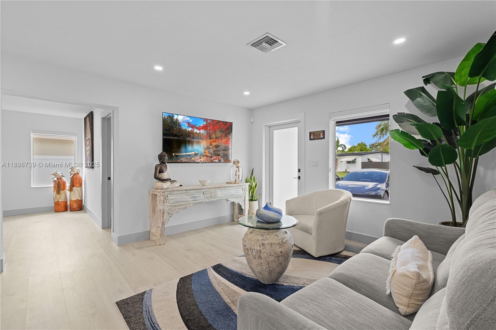 A living room features light wood flooring, a gray sofa, a console table, and a television — 11350 SW 57th St, Miami FL 33173, MIAMI, FL