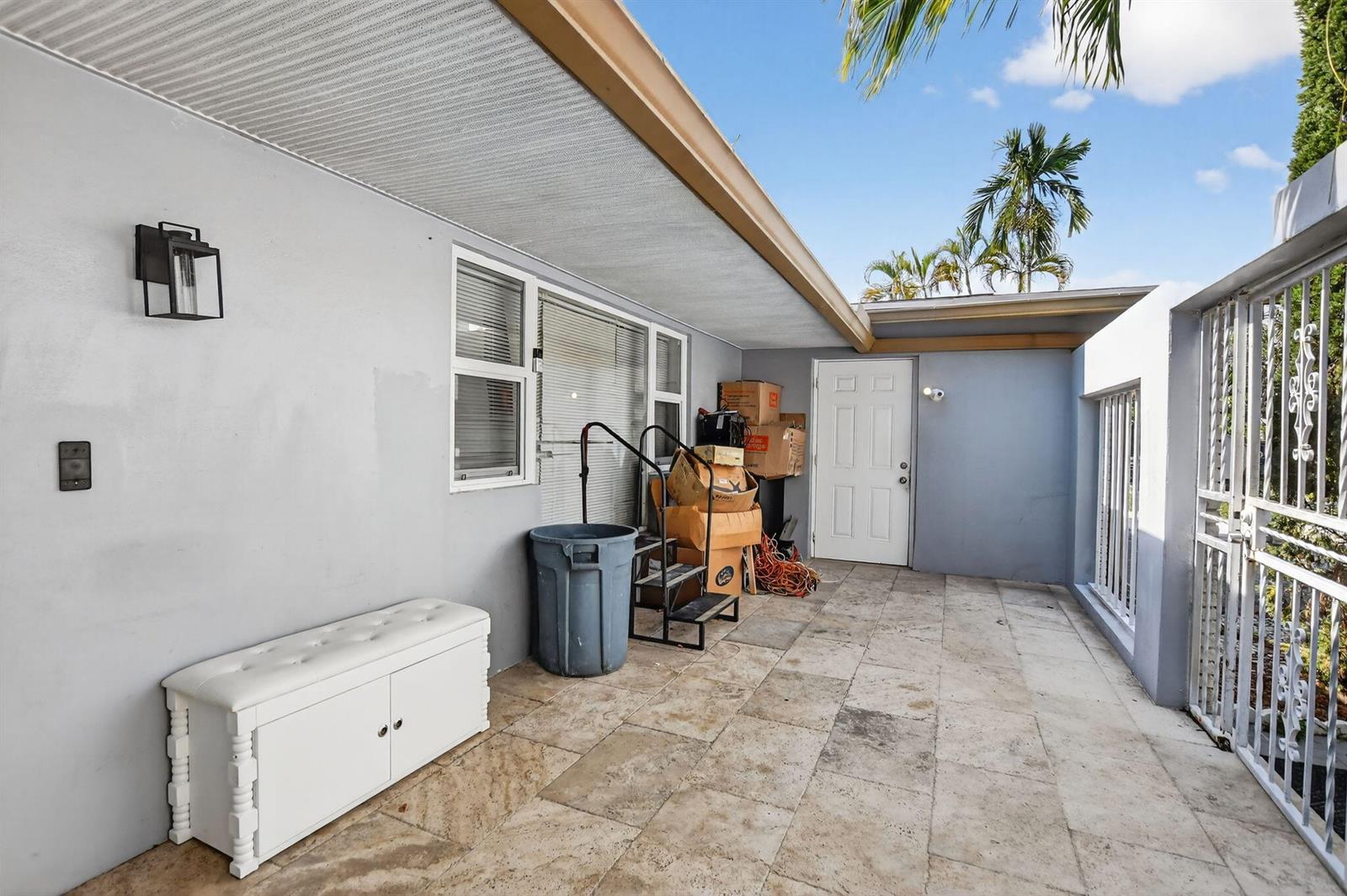 A paved outdoor patio area features a white storage bench, a trash bin, and boxes — 256 SW 11th Place, Boca Raton FL 33432, BOCA RATON, FL