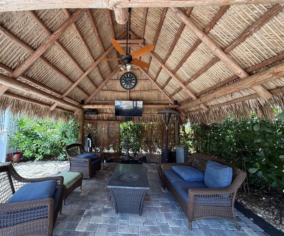A covered outdoor patio with a thatched roof, wicker furniture, a television, and a fireplace — 3520 SW 7TH MANOR UNIT 357, OKEECHOBEE, FL