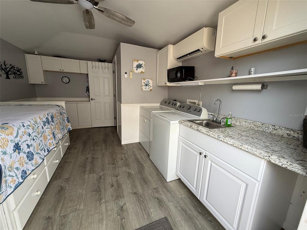 A laundry room with a bed, white cabinets, a sink, and a washer-dryer set — 3520 SW 7TH MANOR UNIT 357, OKEECHOBEE, FL