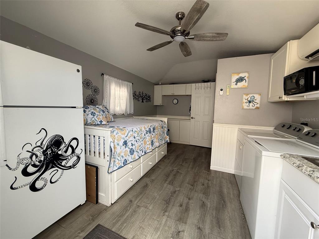 A studio room features a bed, a refrigerator with an octopus decal, and laundry appliances — 3520 SW 7TH MANOR UNIT 357, OKEECHOBEE, FL
