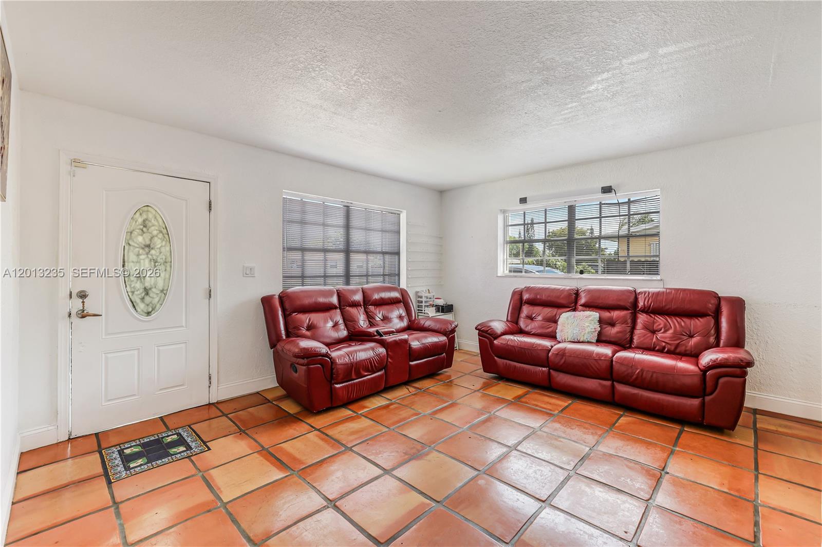 A living room features red leather sofas, white walls, and terracotta tile flooring — 11600 SW 181st Ter, Miami FL 33157, MIAMI, FL